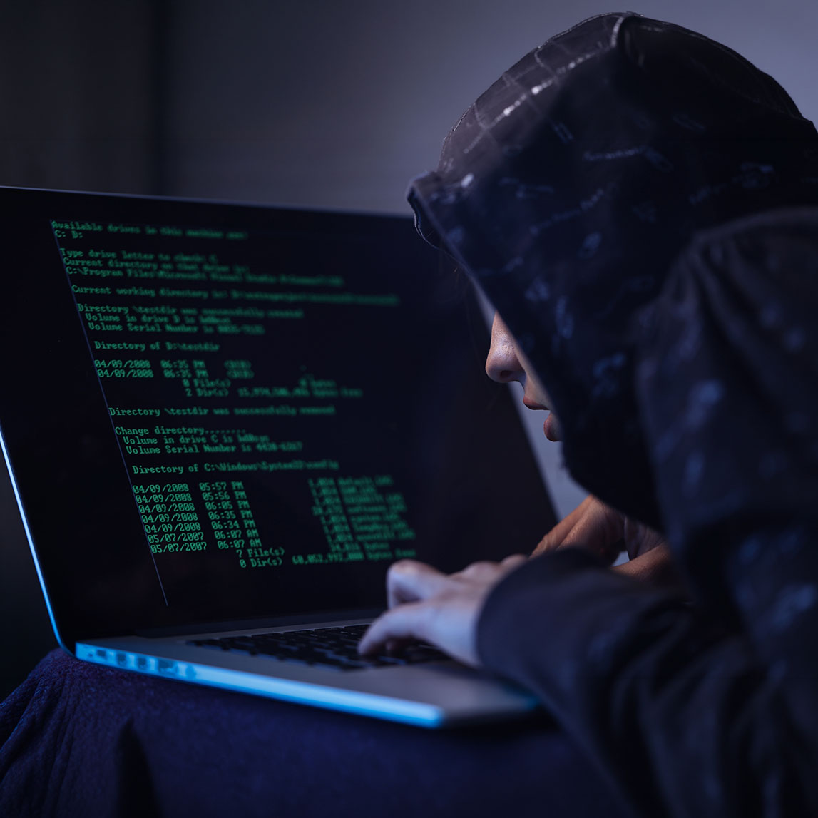 Computer hacker programming software while stealing data on laptop.